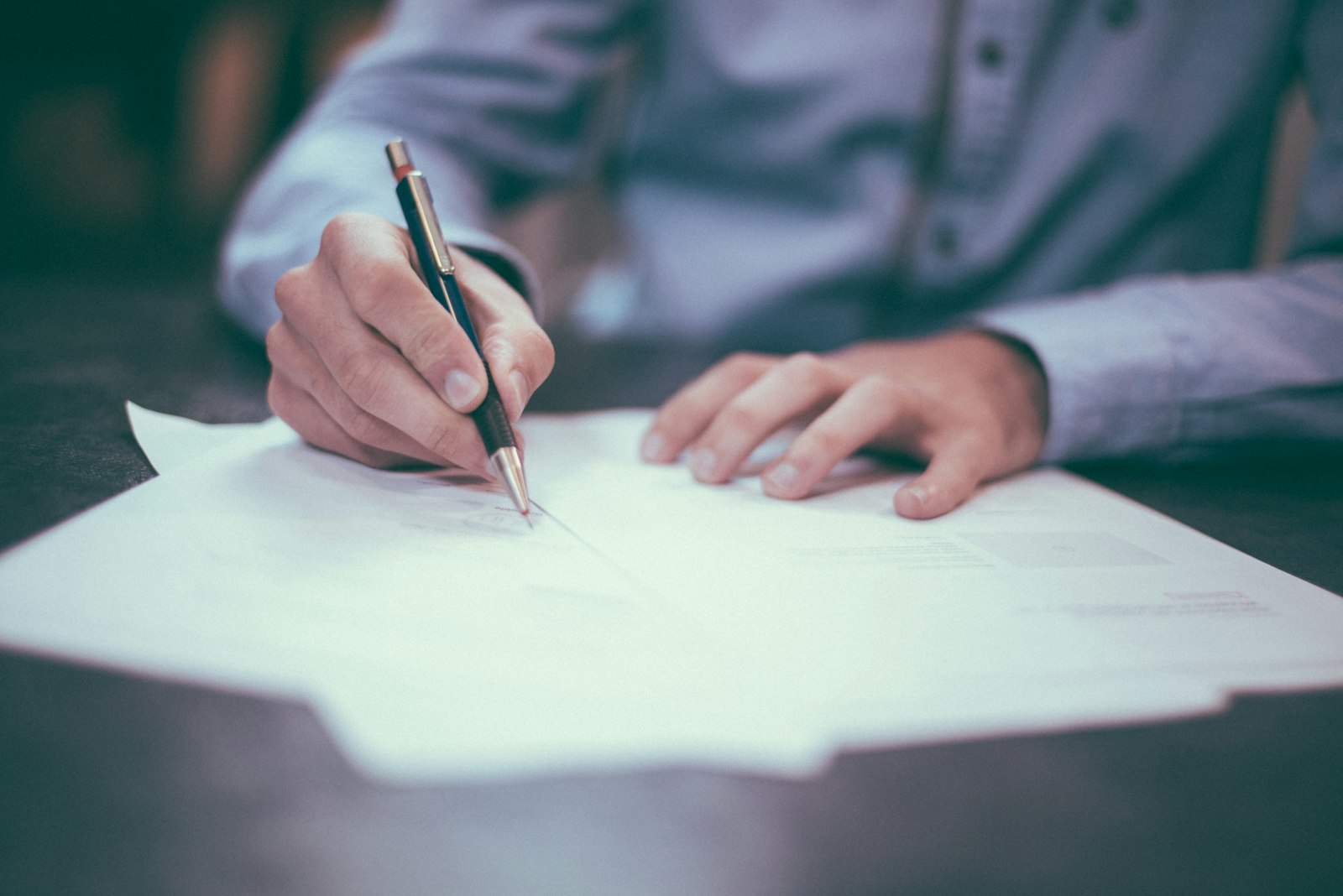 A hand signing a document, representing the point at which an AI platform contract is committed to and the questions that should have been asked before it