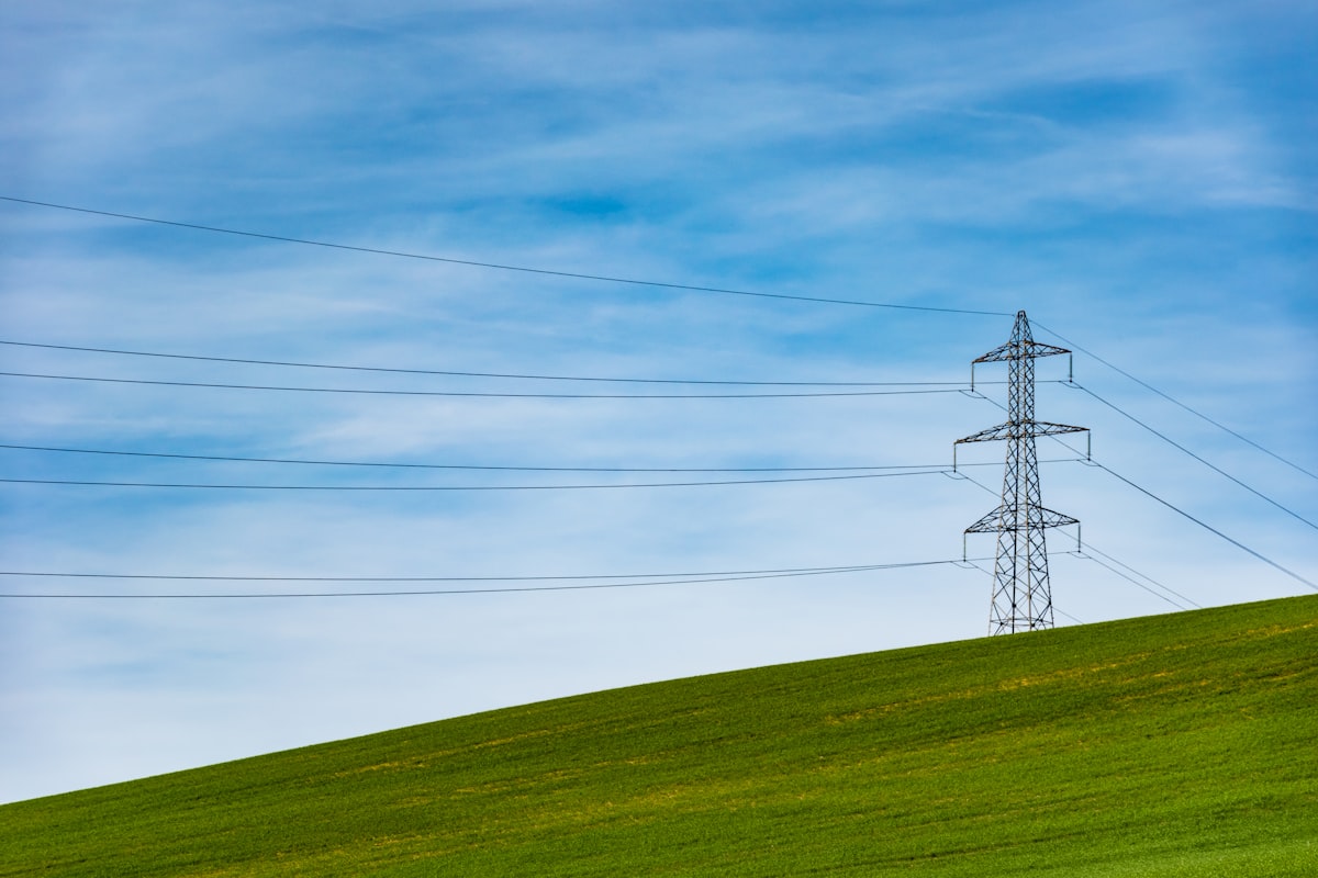 Electrical transmission tower against a clear sky, representing the power grid capacity strain raised by large-scale AI data center proposals in the Caribbean